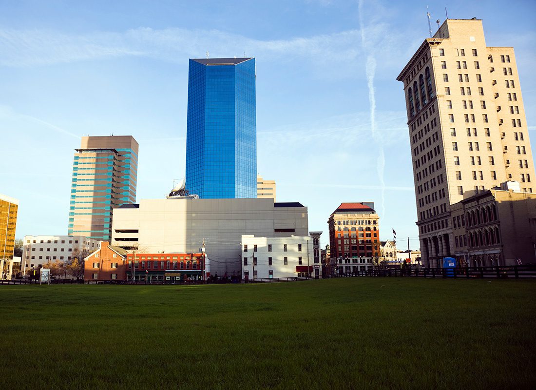 Lexington, KY - Skyline View of Modern and Old Buildings in Downtown Lexington Kentucky in the Early Morning with a Field of Green Grass in Front