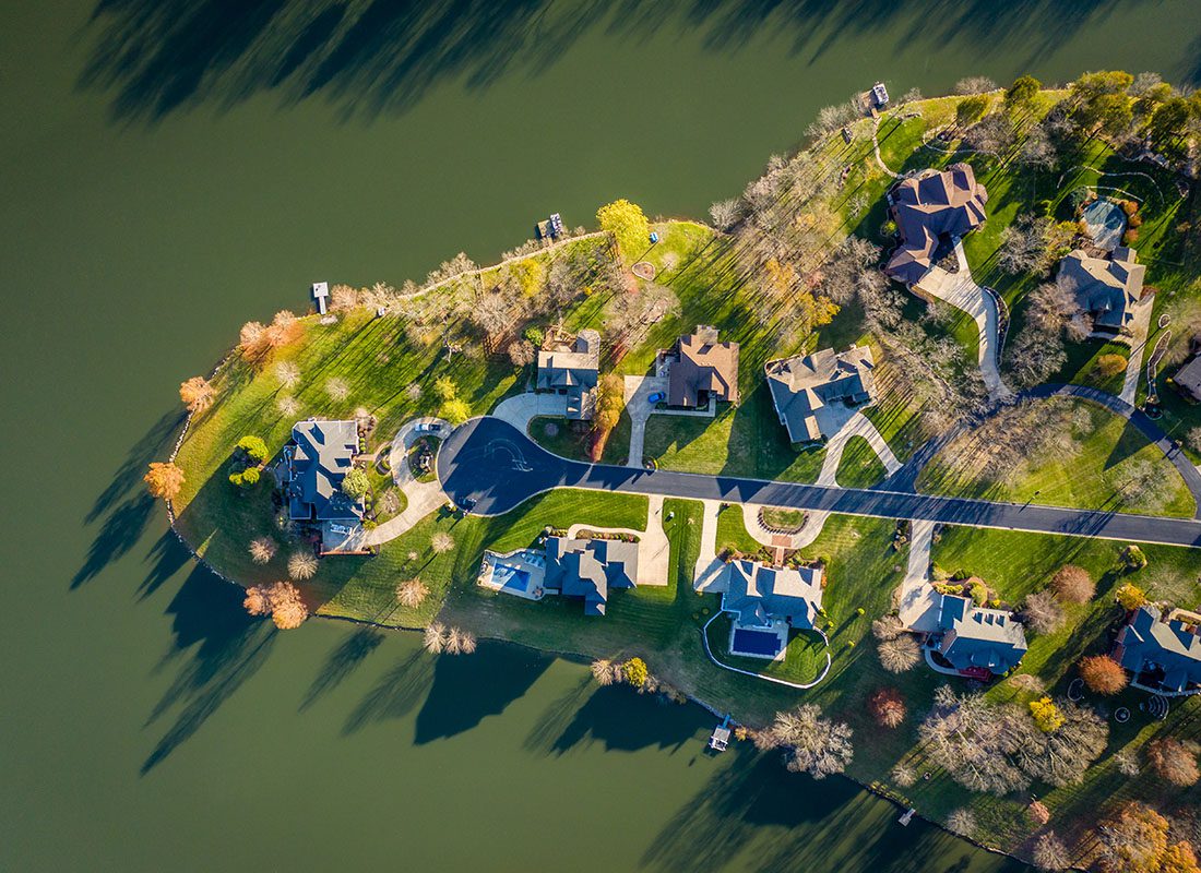 Personal Insurance - Aerial View Looking Down at a Residential Community with Multi Story Luxury Homes by the Lake Surrounded by Green Foliage